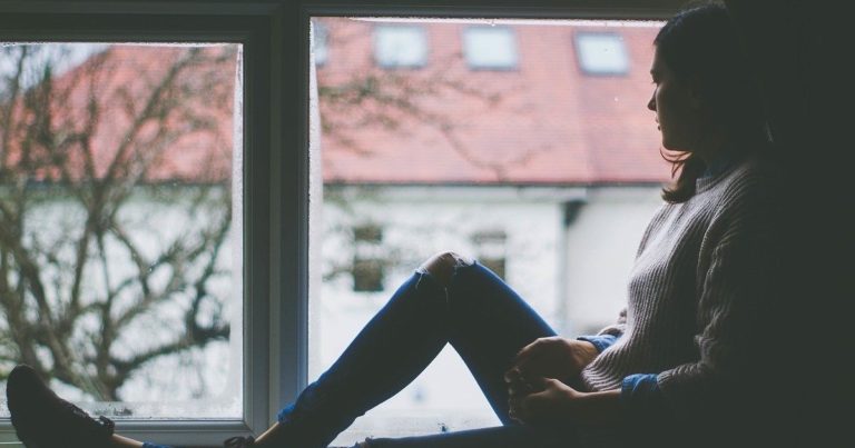 Woman sitting by window alone