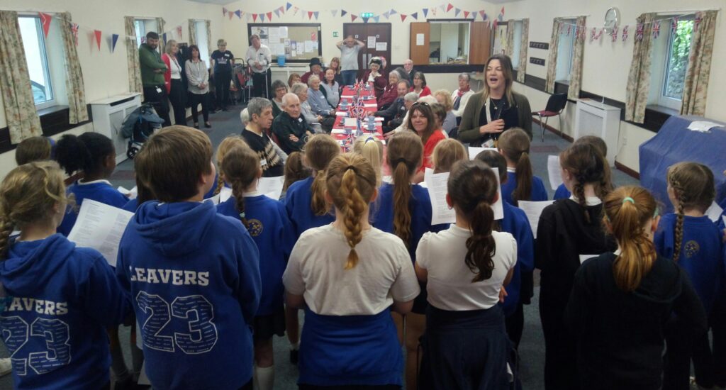 Choir singing to a room of people sat around a table